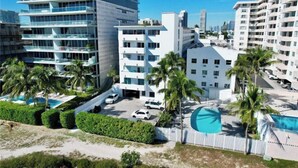 Ein modernes Hotel mit mehreren Etagen, einem Schwimmbad und Palmen.