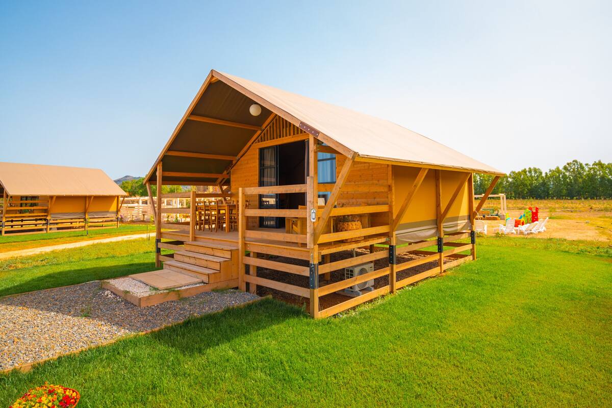 Eine Holzhütte mit Veranda und überdachter Außenbereich mit Sitzgelegenheiten.