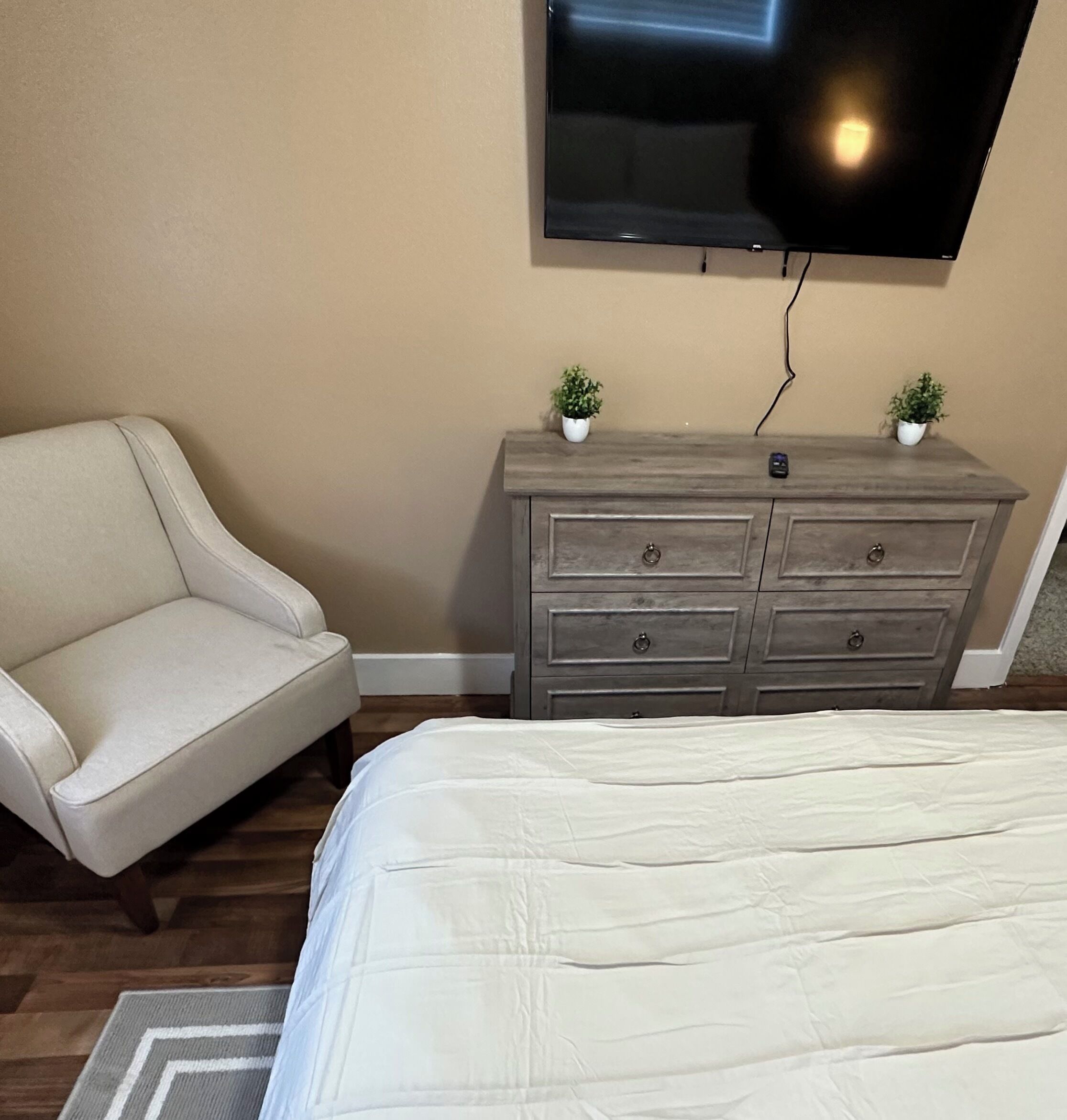 Een slaapkamer met een bed, een bank, een dressoir en een televisie aan de muur.