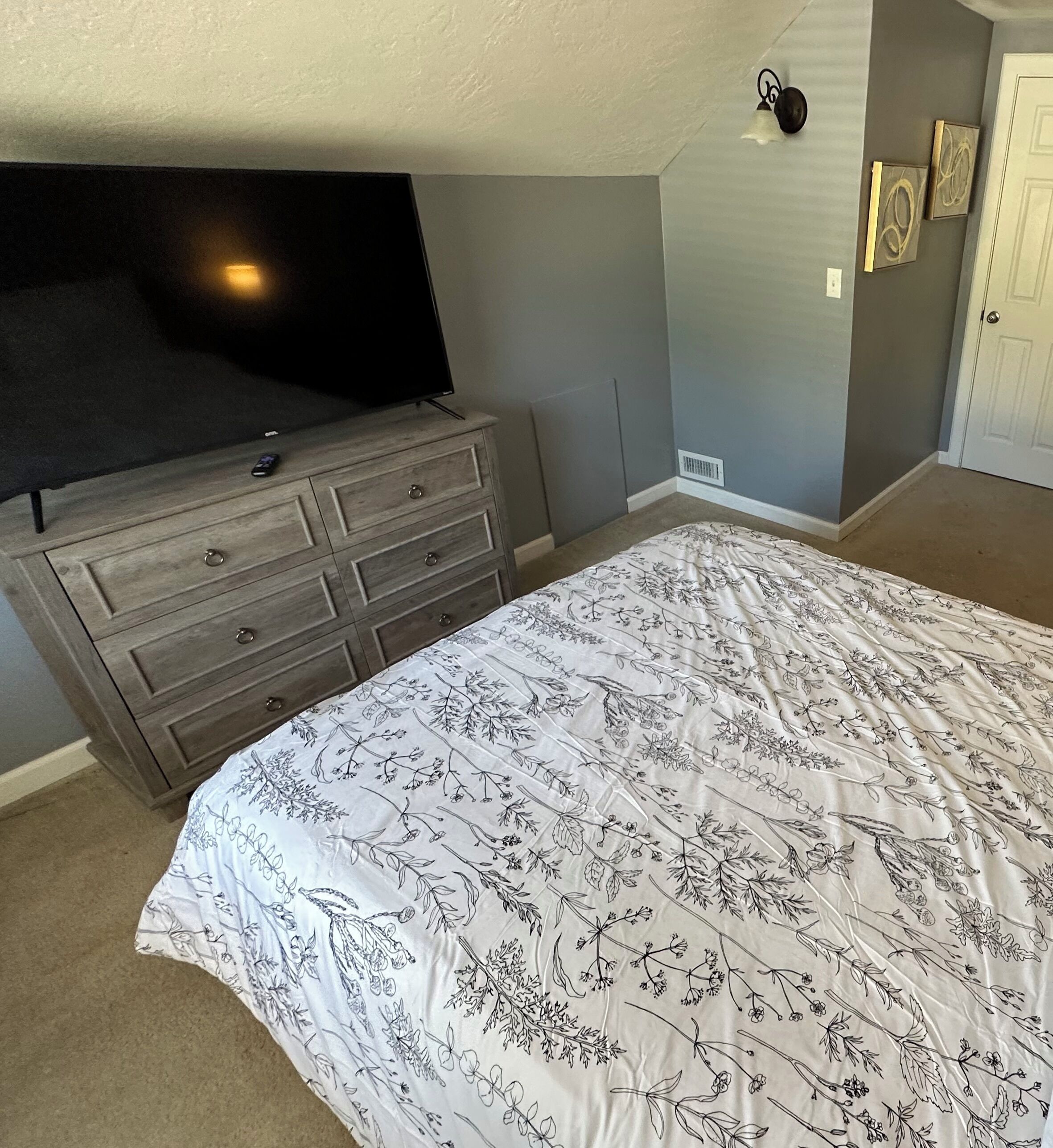 Une chambre à coucher avec un lit, une commode et un téléviseur.