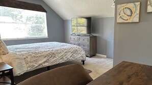 A bedroom with a bed, dresser, and artwork on the wall.
