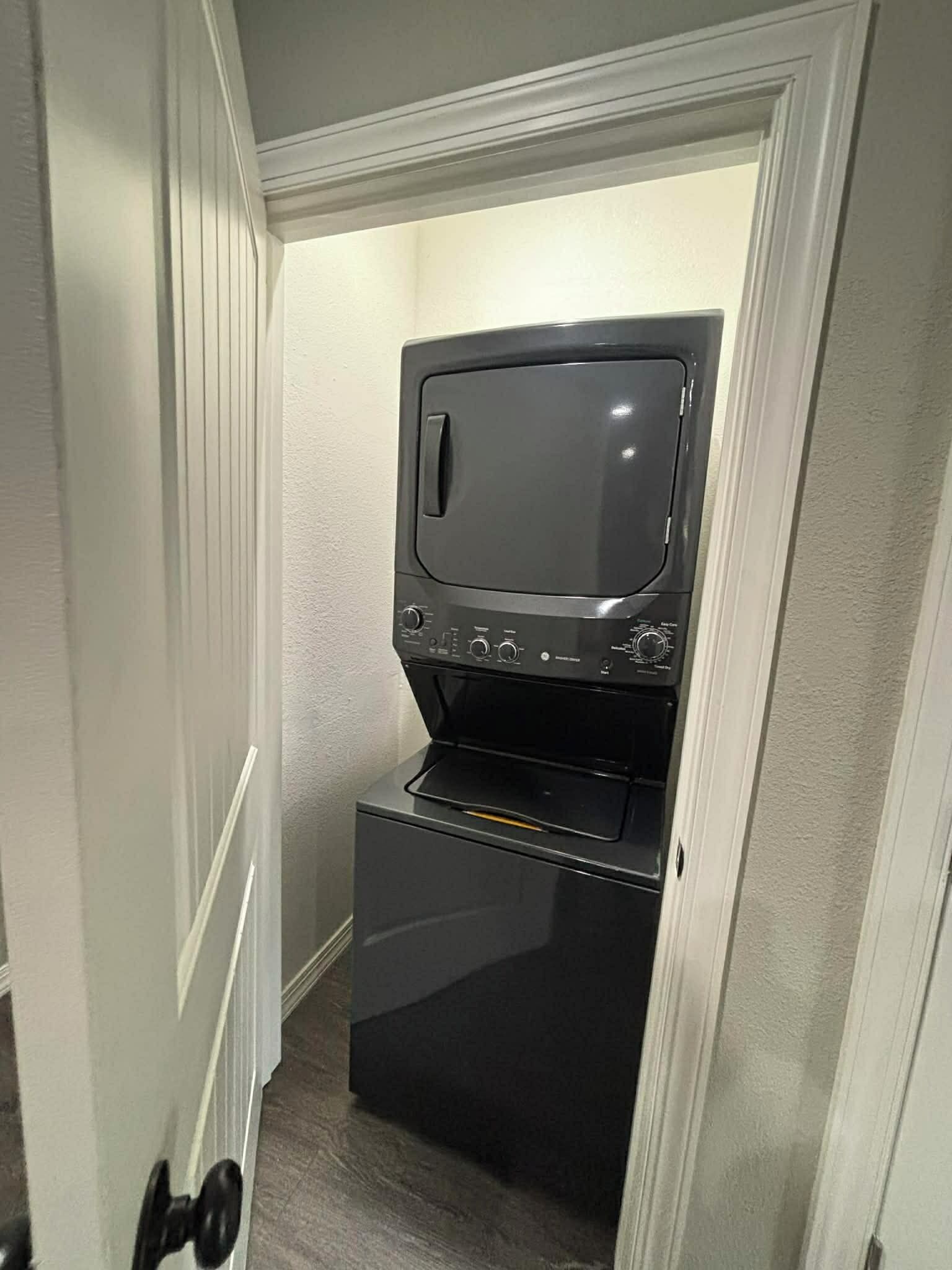 Una kitchenette compacta con microondas y horno, ubicada en un estrecho pasillo de paredes blancas y piso de madera.