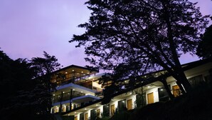 Un immeuble à plusieurs étages, doté de balcons et de grandes fenêtres, entouré d’arbres.