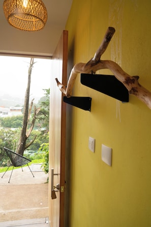 A room with a yellow wall, a wooden door, a black metal bench, and a hanging light fixture. - Hotel con Corazón Monteverde (Monteverde)