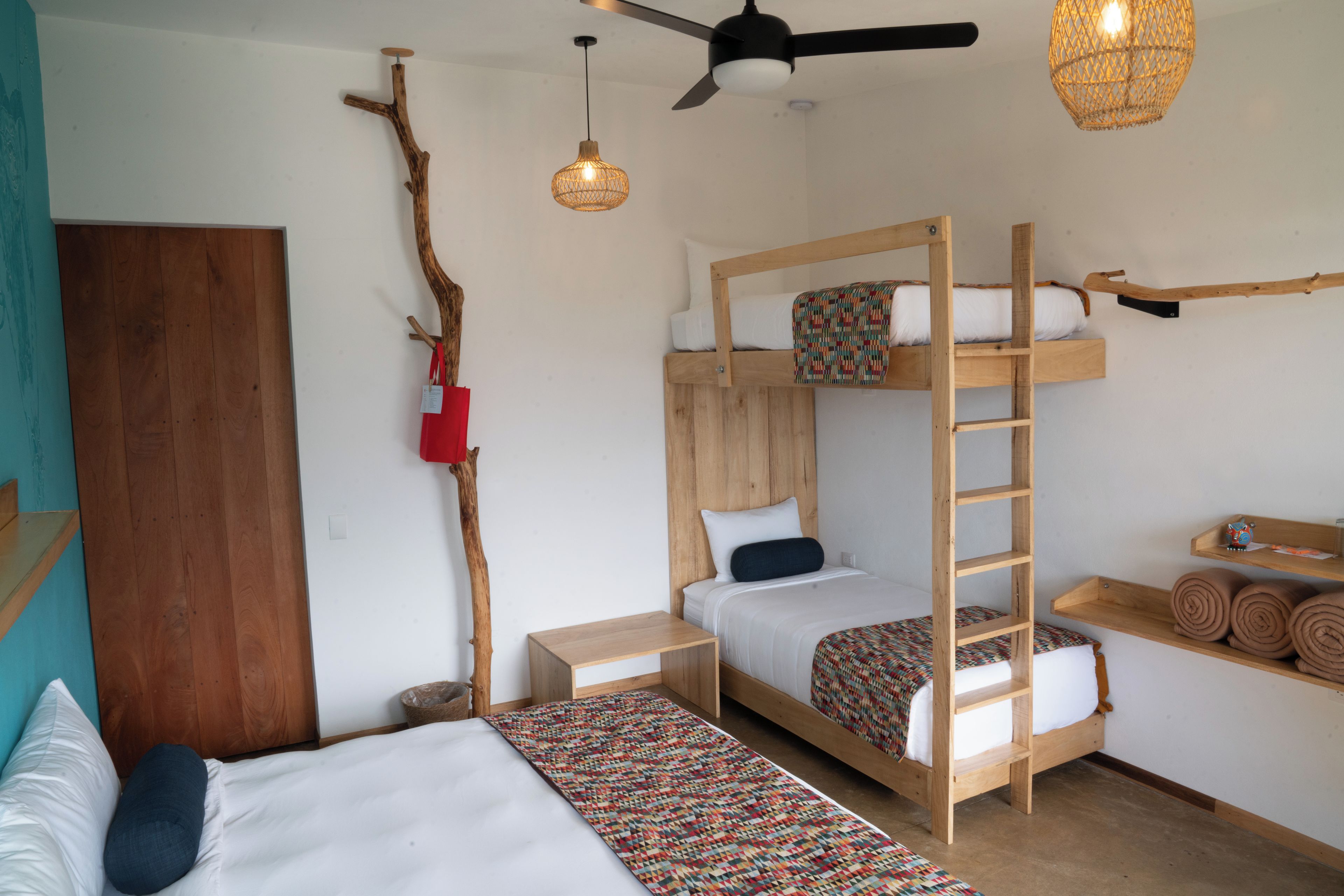 A room with bunk beds, a wooden ladder, a small table, and a hanging light fixture.