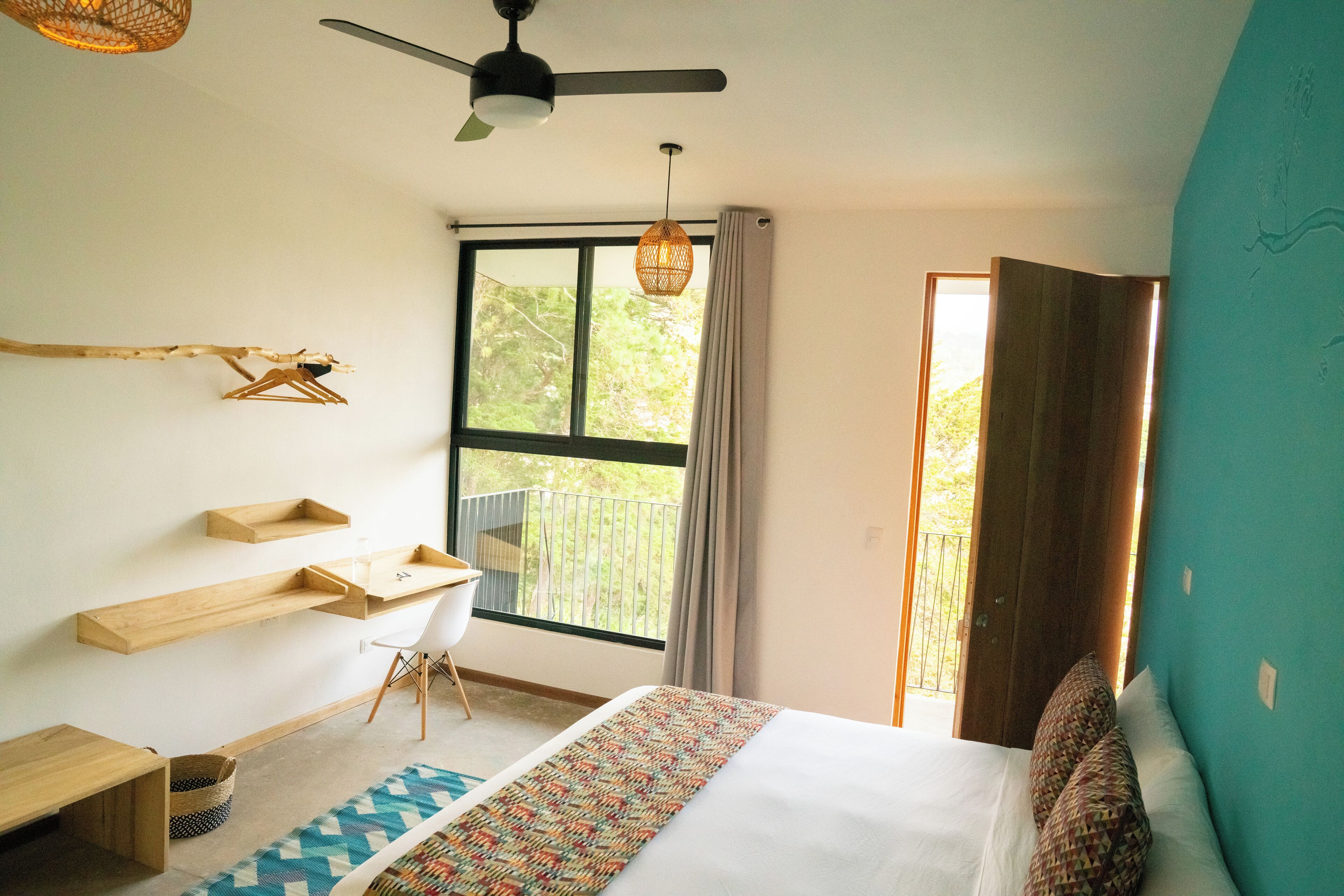 Un dormitorio con cama, escritorio, silla y ventana con vistas a zonas verdes.