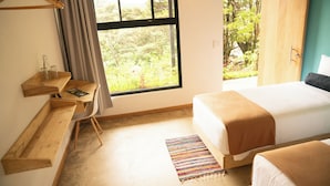 Une chambre avec une grande fenêtre, un bureau en bois, un lit et un tapis coloré.
