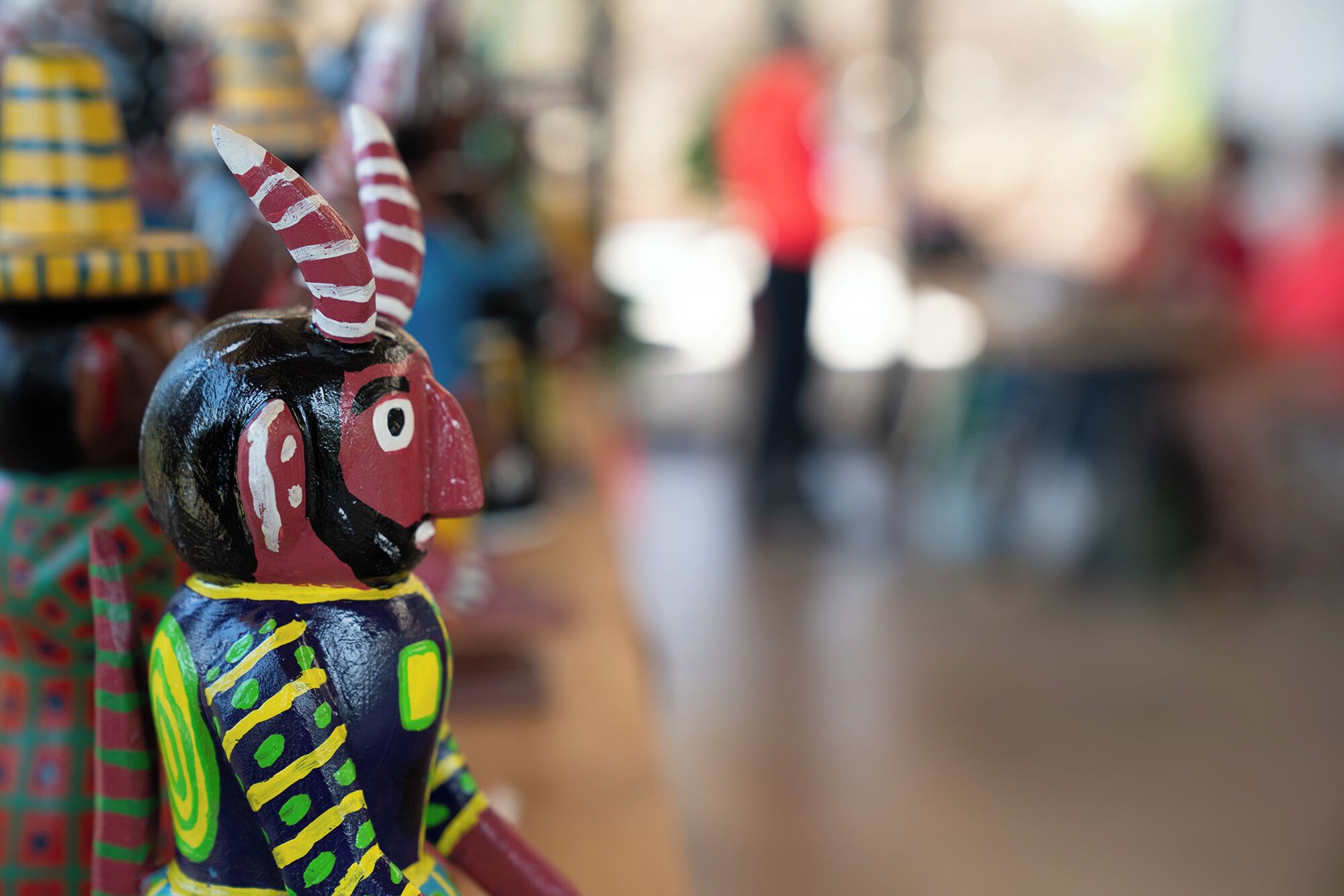 A colorful, hand-painted sculpture of a character with a pointed hat and striped features.