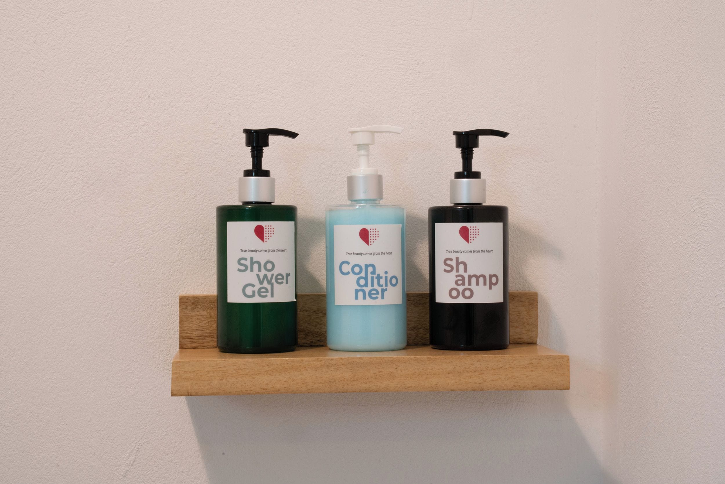 Trois flacons de produits d’hygiène personnelle sont posés sur une étagère en bois.