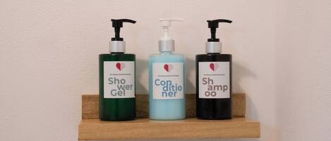 Trois flacons de produits d’hygiène personnelle sont posés sur une étagère en bois.