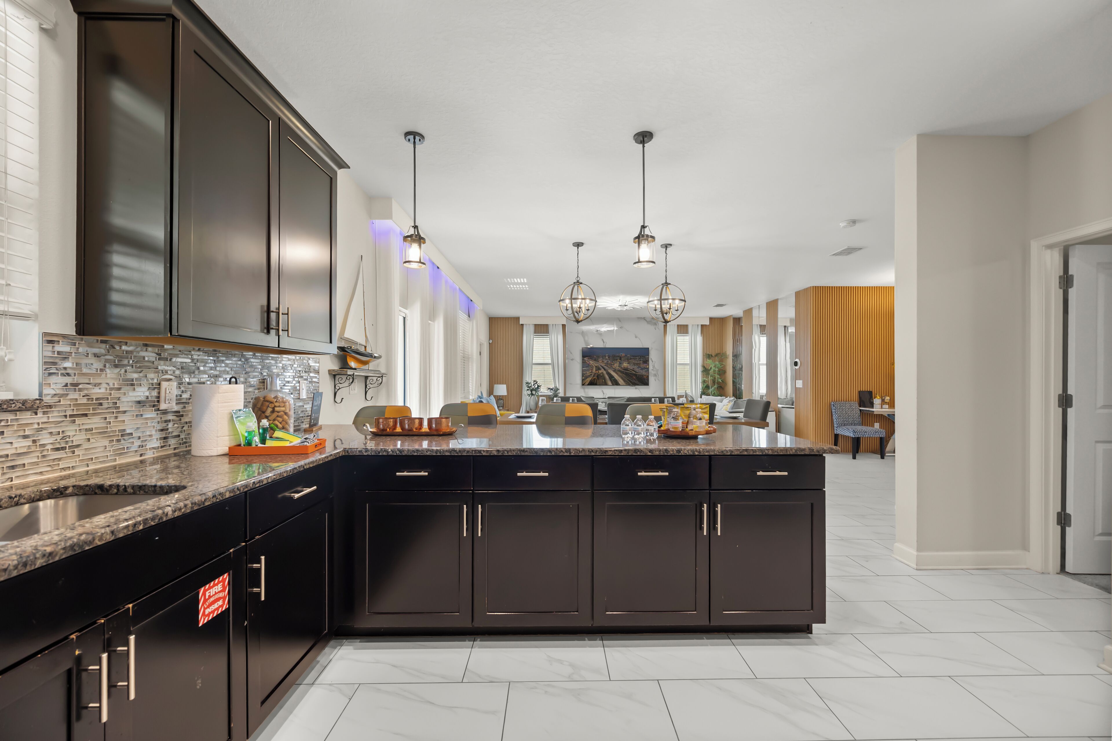 Una cocina moderna con armarios oscuros, una isla grande e iluminación colgante.