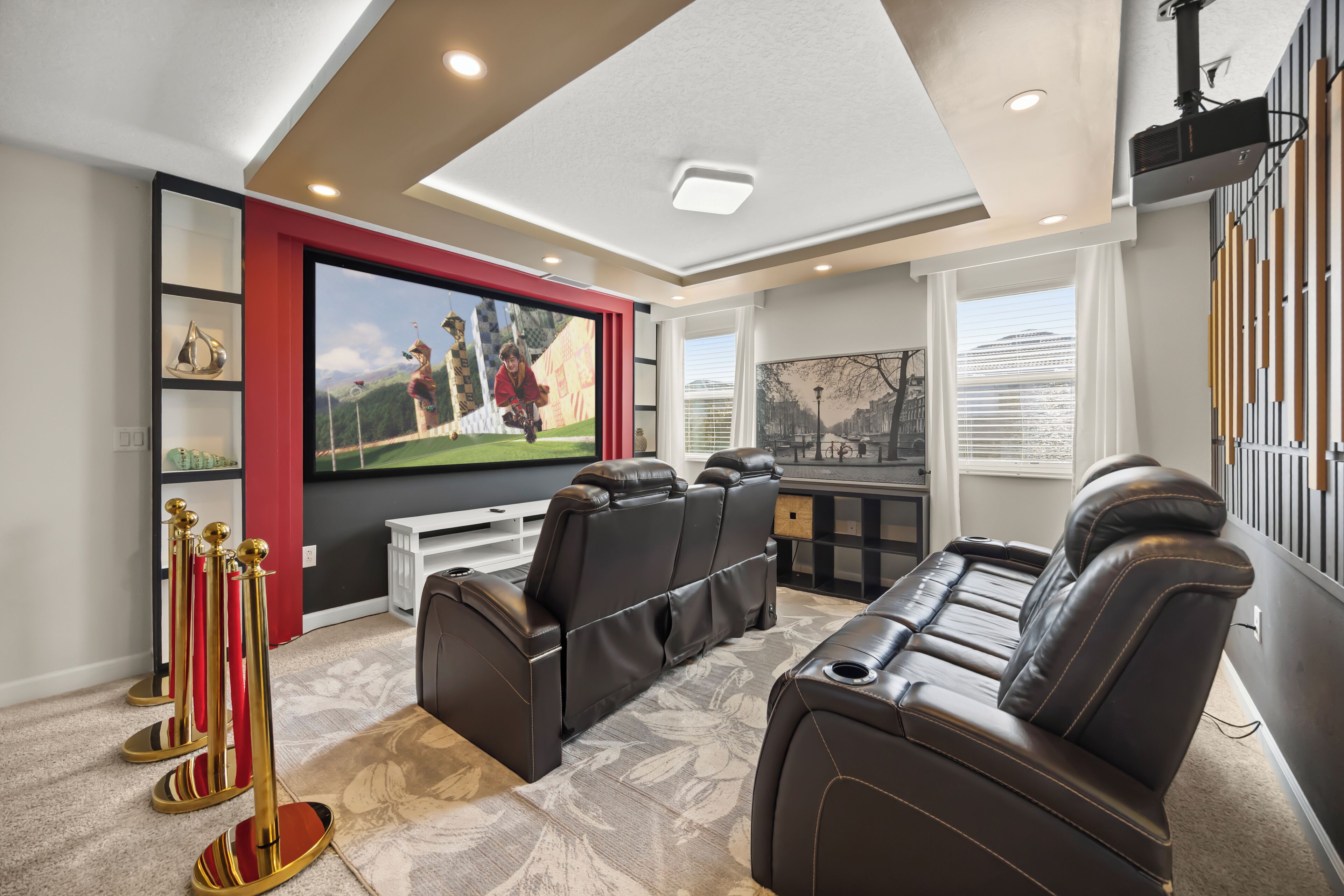 A home theater with a large screen, leather recliners, and a red accent wall.