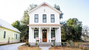 A two-story white house with a front porch, a wooden door, and a number '612' on the door.