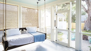 A bedroom with a bed, a ceiling fan, and large windows.
