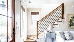 A staircase with wooden steps and black handrails, leading to a landing with a white wall and a framed picture.