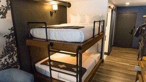 A bunk bed room with a wooden frame, a small desk, and a chair.