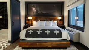 Un dormitorio moderno con una cama grande, un mural con noche estrellada y vistas de la ciudad.