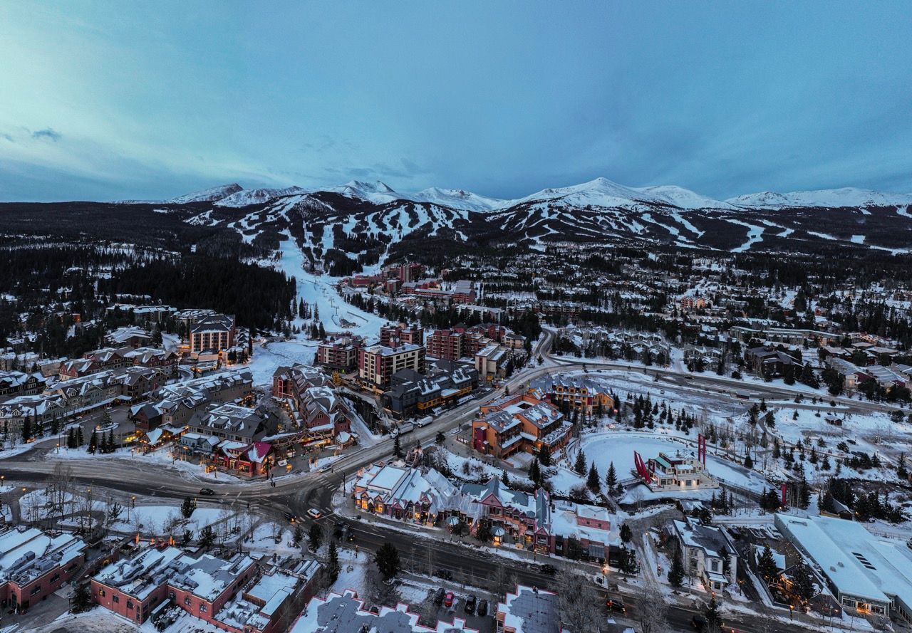A town with buildings and roads, surrounded by snow-covered mountains.