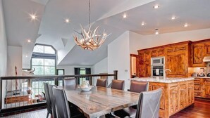 Una cocina moderna con armarios de madera, una isla central y un comedor con una mesa grande y sillas.