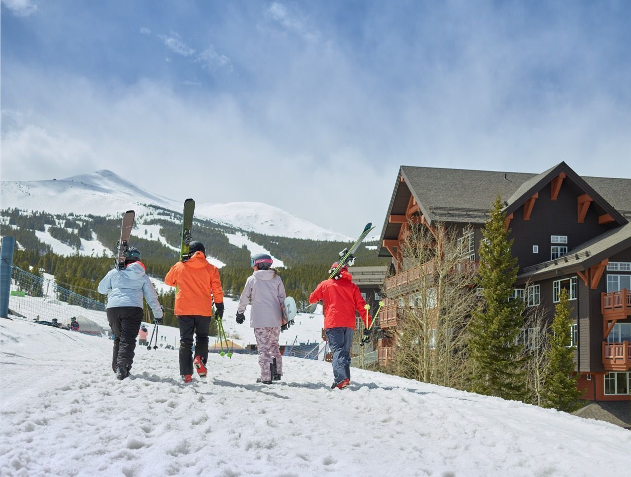 Un grupo de personas con esquíes caminando hacia un refugio de montaña.