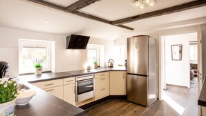 A modern kitchen with a built-in oven, stainless steel refrigerator, and a large island with a sink. - Anno 1895 - Holiday home for up to 4 people, pets welcome (Manslagt)