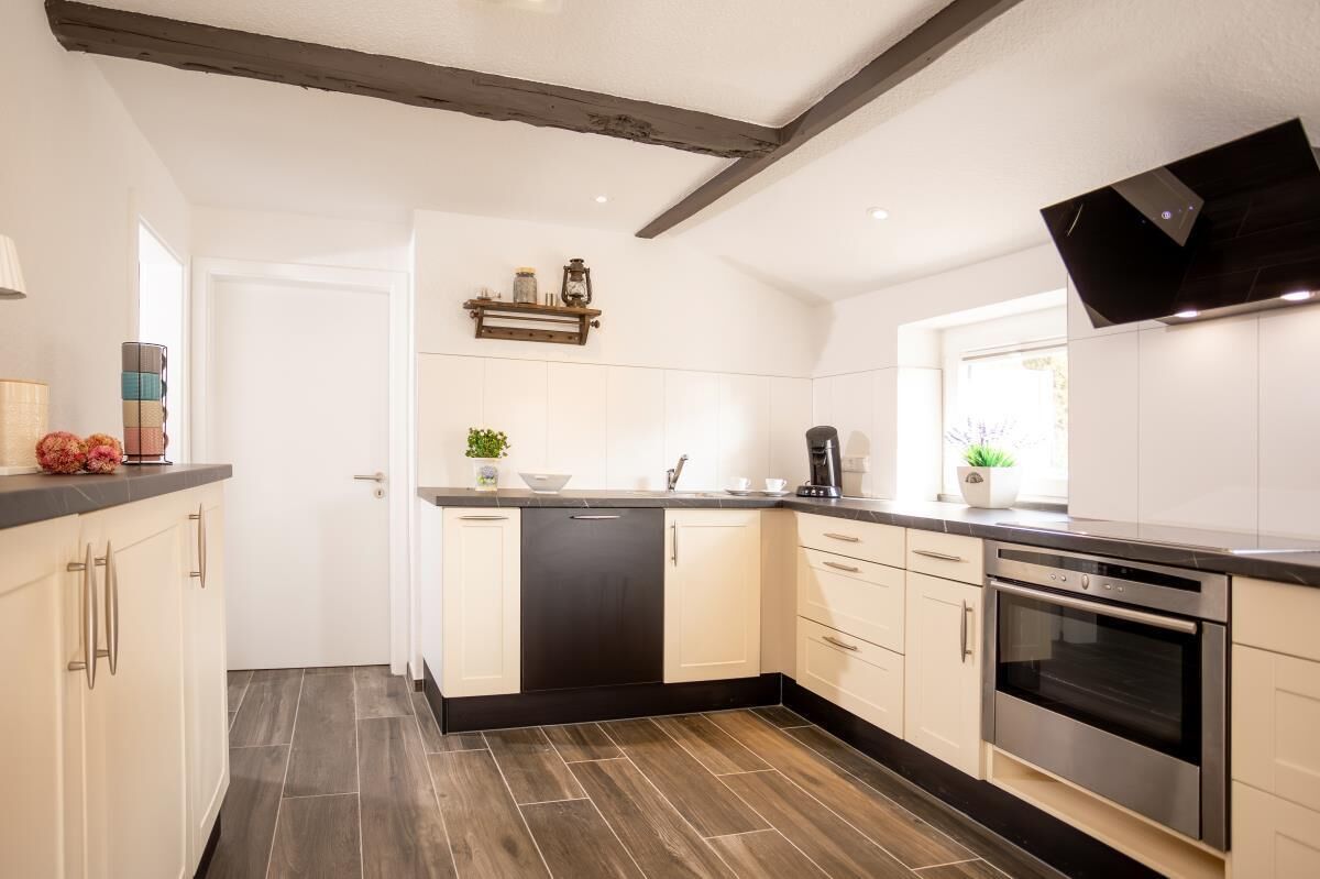 A modern kitchen with white cabinetry, a black countertop, and a built-in oven.