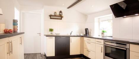A modern kitchen with white cabinetry, a black countertop, and a built-in oven.