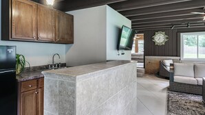 Eine Küche mit Holzausstattung, einer integrierten Kochinsel und einem an der Wand befestigten Flachbildfernseher.