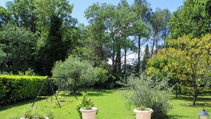 A garden with a stone wall, potted plants, and a swing set.