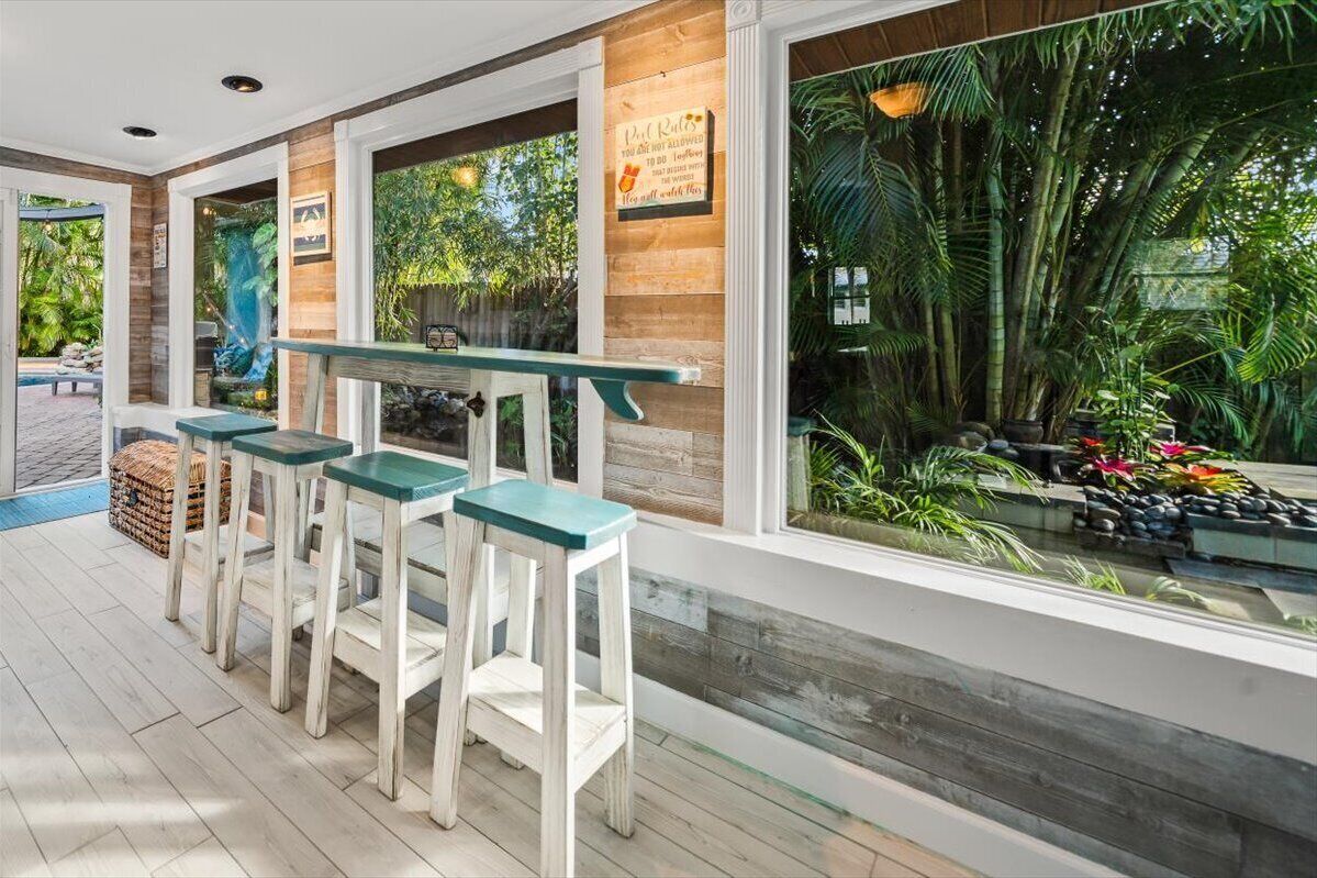 Un espace bar avec des meubles en bois et en verre, une vue sur des plantes tropicales et un panneau sur le mur.