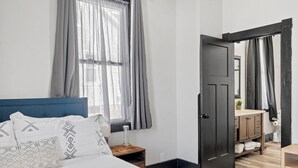 A bedroom with a bed, a nightstand, a dresser, and a door leading to another room. - The WashMO Hospitality House WALK to riverfront, shopping, wine shuttle, HOT TUB (Washington)