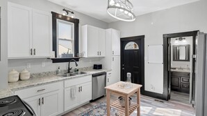 A modern kitchen with white cabinets, a granite countertop, a built-in dishwasher, and a black-framed door. - The WashMO Hospitality House WALK to riverfront, shopping, wine shuttle, HOT TUB (Washington)