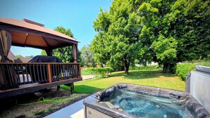 A hot tub in a backyard with a wooden deck and a covered seating area. - The WashMO Hospitality House WALK to riverfront, shopping, wine shuttle, HOT TUB (Washington)