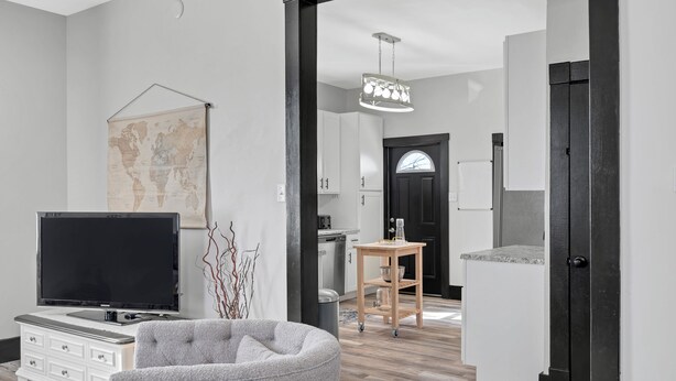 A modern living room with a flat-screen TV, a grey armchair, a world map on the wall, and a wooden table with a lamp. - The WashMO Hospitality House WALK to riverfront, shopping, wine shuttle, HOT TUB (Washington)