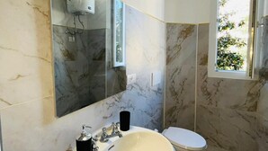 Un baño con un lavamanos blanco, un espejo y un inodoro.