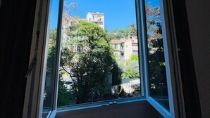 Una habitación con un amplio ventanal que ofrece vistas a edificios y árboles.