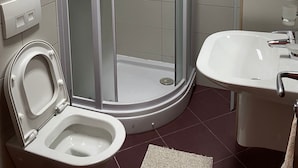 A bathroom with a glass-enclosed shower, a toilet, a sink, and a towel rack. - Couple Studio PG (Podgorica)