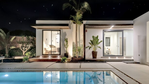 A modern house with a swimming pool, large windows, and a well-maintained garden.