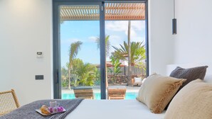 A bedroom with a large bed, a breakfast tray, and a view of a pool and outdoor area.