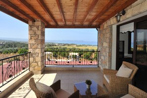 A balcony with stone pillars, wicker furniture, and a view of the landscape. - Sunset View Villa in Argaka (Argaka)