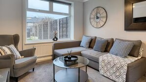 A modern living room with a sofa, armchair, and coffee table. A large window provides a view of the outside. - Last Min Weekend Stay, Trafford, Pets Welcome (Sale)
