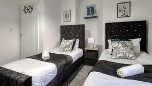 A hotel room with two beds, each with a black headboard and white bedding. There is a nightstand with a lamp between the beds. - Last Min Weekend Stay, Trafford, Pets Welcome (Sale)