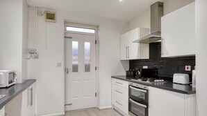 A modern kitchen with white cabinets, a black countertop, a microwave, a stove, and a toaster. - Last Min Weekend Stay, Trafford, Pets Welcome (Sale)
