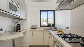 Una cocina moderna con microondas integrado, cocina a gas y ventana con vista a la ciudad.