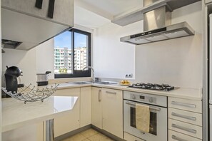 Una cocina moderna con estufa a gas, horno y pileta de acero inoxidable.