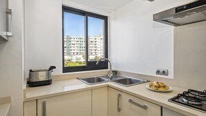 Cocina moderna con ventana, electrodomésticos de acero inoxidable y vistas a edificios.