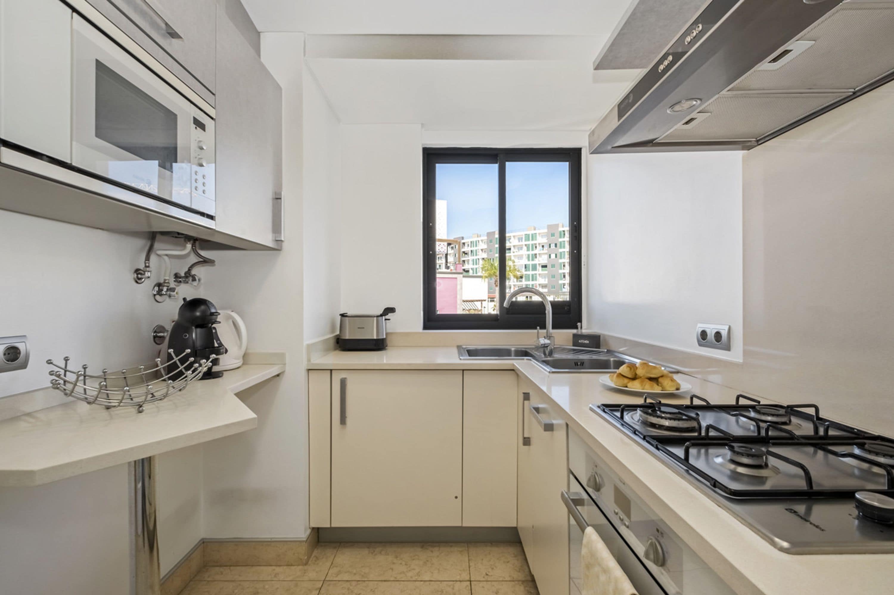 Una cocina moderna con microondas integrado, cocina a gas y ventana con vista a la ciudad.