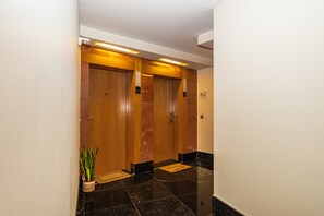 A hallway with three wooden doors, each marked with a floor number. - F rum Ocean View 5B by Homie (Funchal)