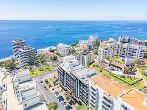A coastal cityscape with modern high-rise buildings, a marina, and a clear view of the sea.