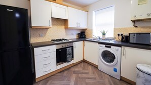 Une cuisine compacte équipée d’un réfrigérateur, d’une cuisinière, d’un évier et d’un lave-linge.